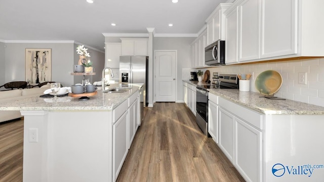 kitchen with stainless steel appliances, white cabinetry, a center island with sink, and sink