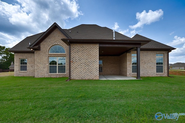 back of house featuring brick siding, a yard, and a patio