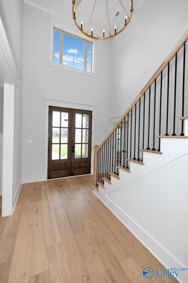 entryway featuring hardwood / wood-style floors, a high ceiling, an inviting chandelier, and stairs