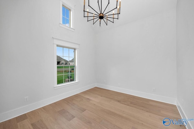 unfurnished dining area featuring light wood finished floors, plenty of natural light, baseboards, and a notable chandelier