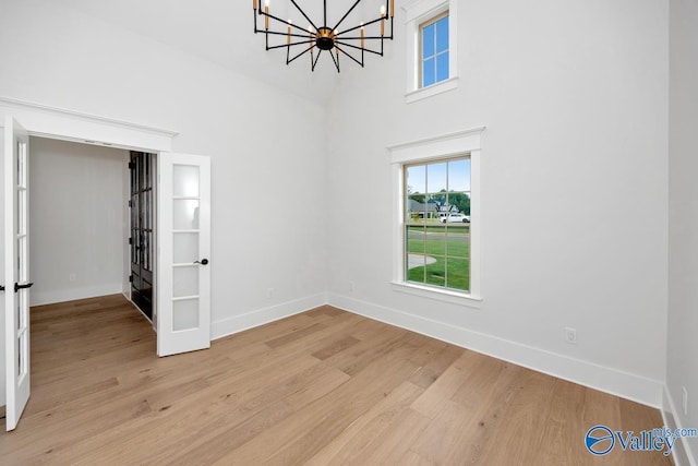interior space featuring light wood-style floors, baseboards, and a notable chandelier