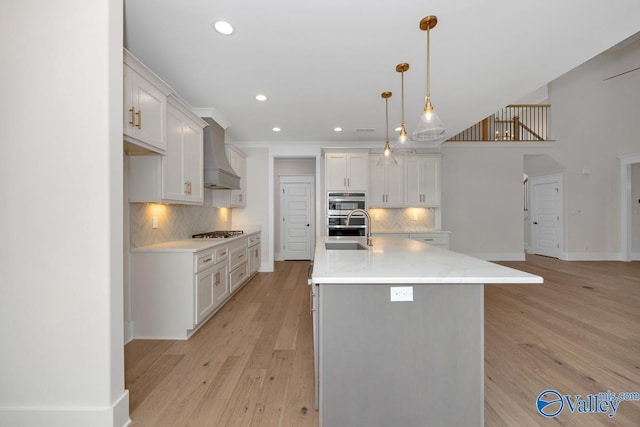 kitchen featuring custom exhaust hood, a sink, light countertops, backsplash, and appliances with stainless steel finishes