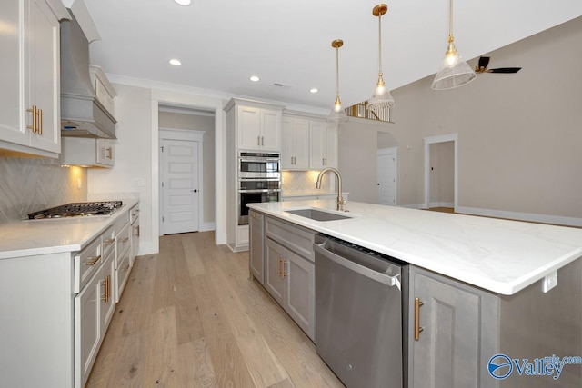 kitchen with stainless steel appliances, a sink, recessed lighting, decorative backsplash, and premium range hood