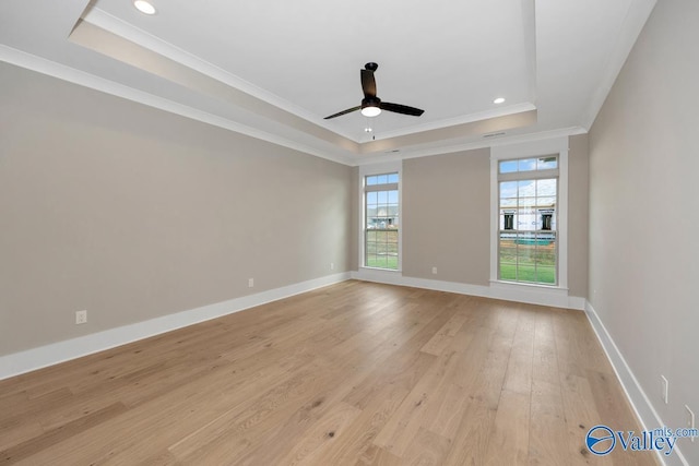 empty room with a tray ceiling, light wood-type flooring, recessed lighting, ceiling fan, and ornamental molding