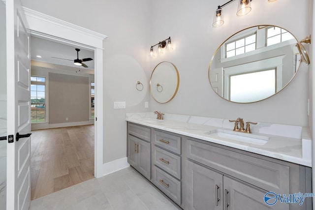 full bathroom featuring ceiling fan, baseboards, a sink, and double vanity