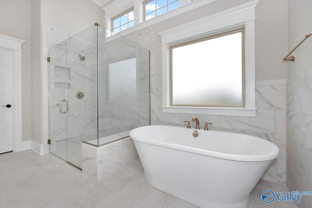 full bathroom with a freestanding bath, a marble finish shower, and tile walls