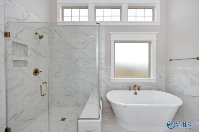 bathroom featuring a freestanding bath, a shower stall, and tile walls