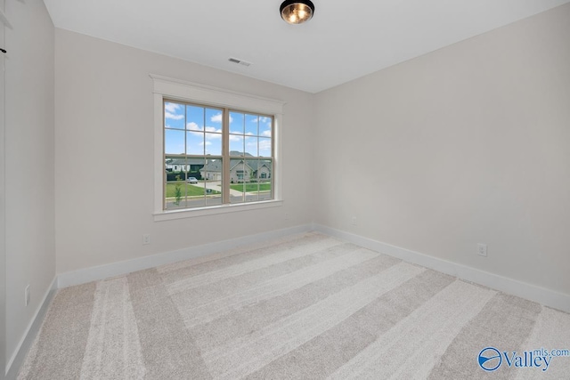 empty room featuring visible vents, carpet flooring, and baseboards