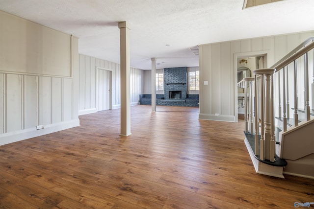 unfurnished living room featuring dark hardwood / wood-style flooring, a textured ceiling, and a brick fireplace