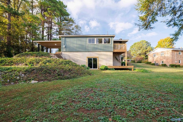 back of property with a lawn, a balcony, and a carport