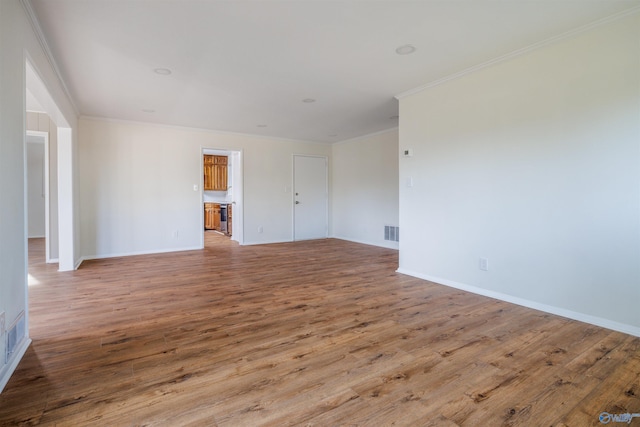 empty room featuring wood-type flooring and crown molding