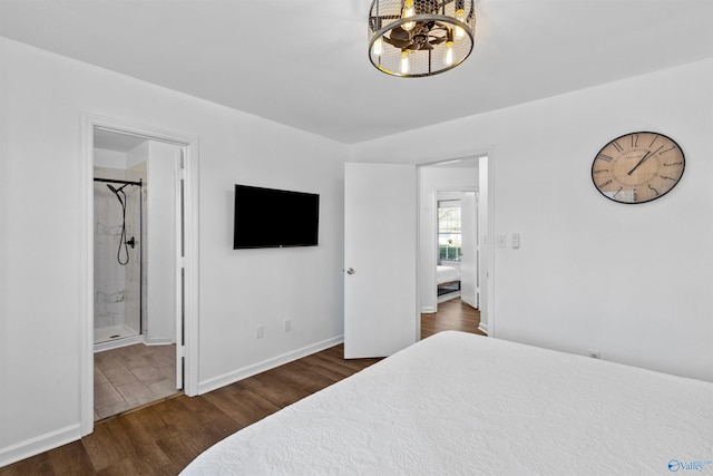 bedroom featuring ensuite bath, an inviting chandelier, wood finished floors, and baseboards