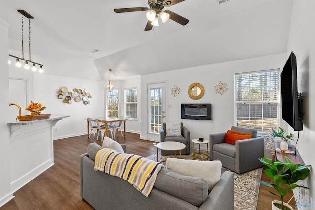 living room featuring visible vents, lofted ceiling, plenty of natural light, and dark wood-type flooring