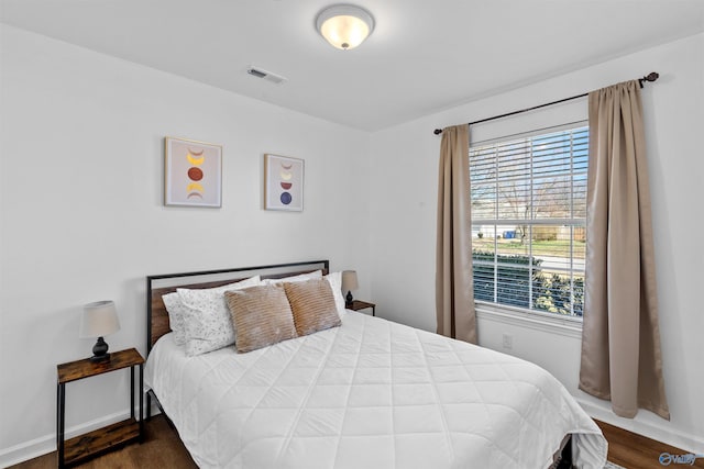 bedroom featuring wood finished floors, visible vents, and baseboards