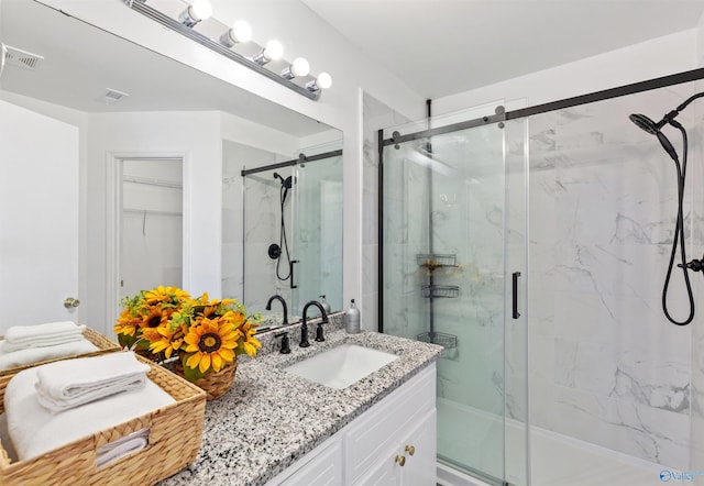 full bath with a marble finish shower, visible vents, and vanity