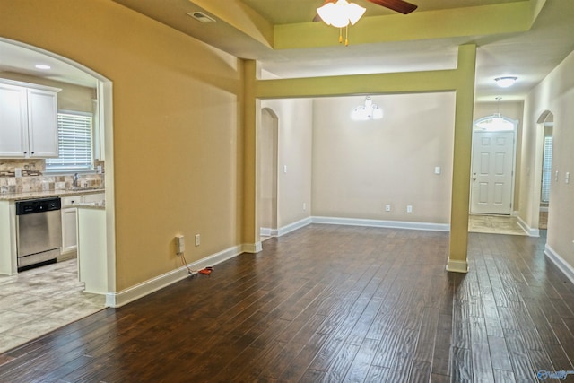 interior space featuring arched walkways, visible vents, dark wood-type flooring, a sink, and baseboards