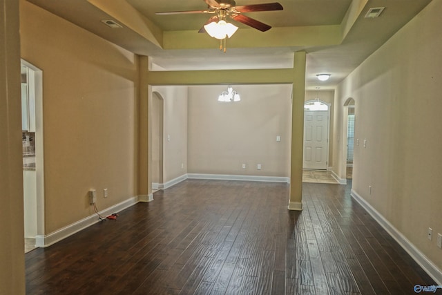 interior space featuring arched walkways, a tray ceiling, dark wood-style flooring, and visible vents