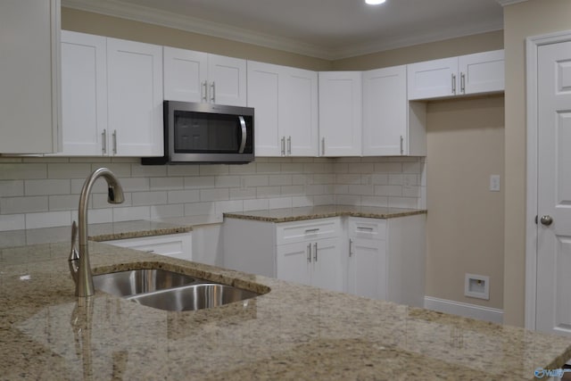 993 Old Cullman Rd, Arab, AL 35016 - kitchen with stainless steel microwave, a sink, light stone counters, white cabinets, and ornamental molding