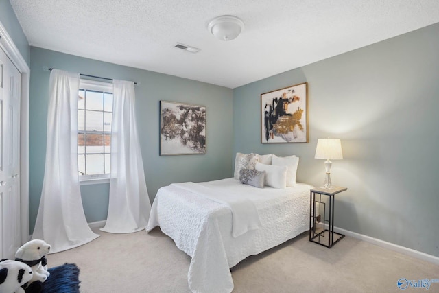 carpeted bedroom with baseboards, a closet, visible vents, and a textured ceiling