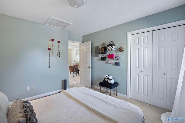 bedroom with a textured ceiling, light carpet, baseboards, a closet, and attic access