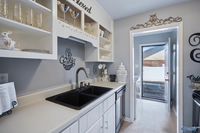 kitchen featuring a sink, white cabinetry, light countertops, stainless steel dishwasher, and open shelves
