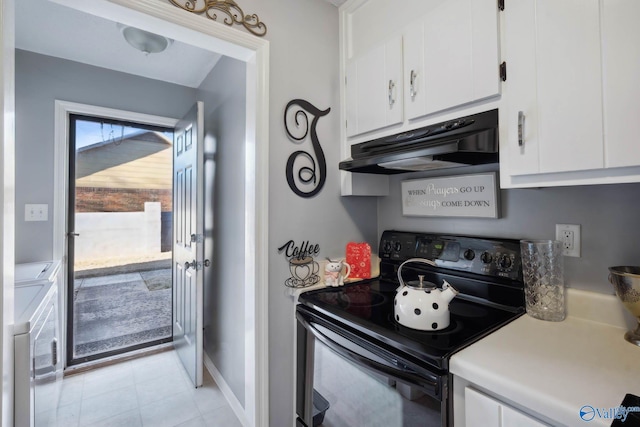 kitchen with black electric range oven, independent washer and dryer, light countertops, under cabinet range hood, and white cabinetry