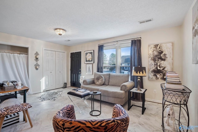 living room featuring visible vents, a textured ceiling, and baseboards