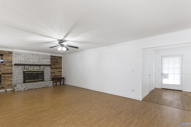 unfurnished living room with hardwood / wood-style floors, crown molding, a fireplace, and ceiling fan