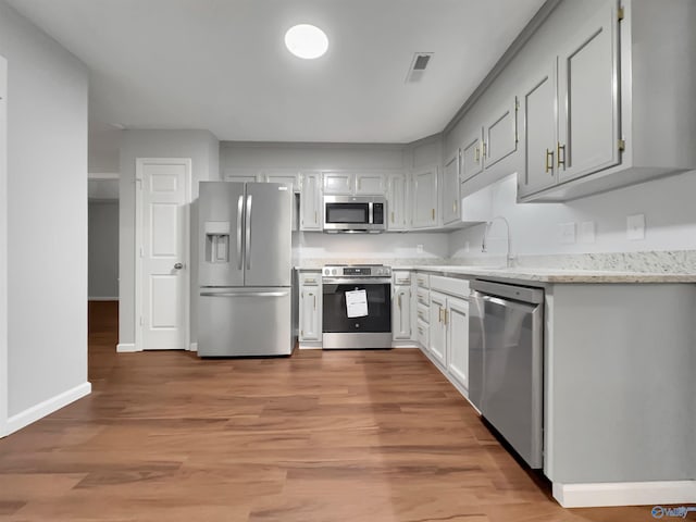 107 Patra Dr, Madison, AL 35758 - kitchen with stainless steel appliances, light wood-style floors, and light stone counters