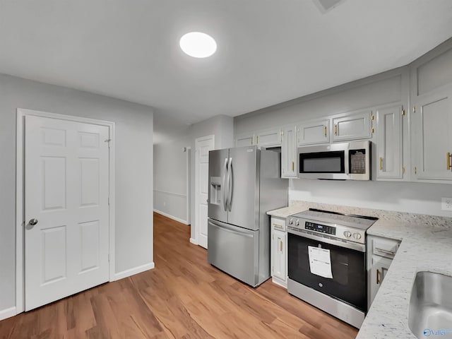 107 Patra Dr, Madison, AL 35758 - kitchen featuring appliances with stainless steel finishes, light wood finished floors, and light stone countertops