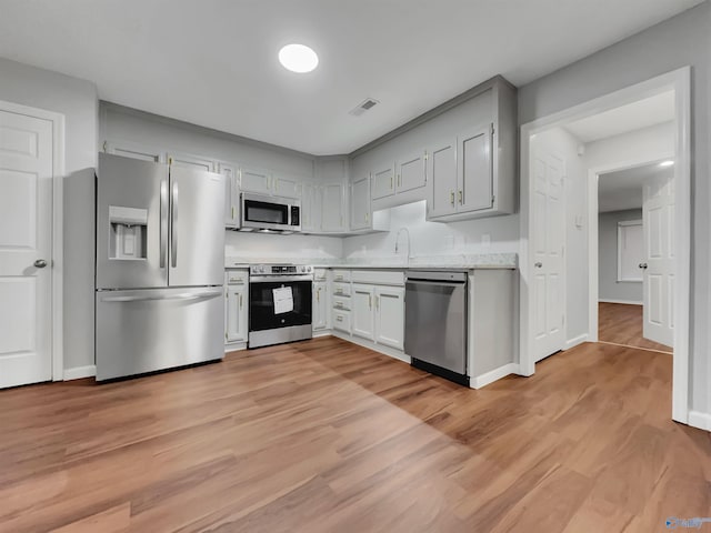 107 Patra Dr, Madison, AL 35758 - kitchen with stainless steel appliances, light countertops, and light wood-style flooring