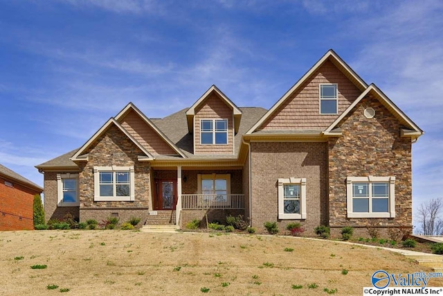 craftsman house with a porch, brick siding, and stone siding