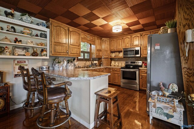 7250 County Road 113, Centre, AL 35960 - kitchen featuring a peninsula, appliances with stainless steel finishes, decorative backsplash, a breakfast bar area, and dark wood-style floors