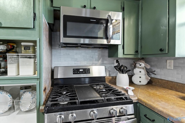 kitchen with backsplash, green cabinets, and stainless steel appliances