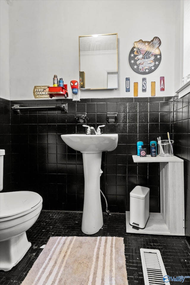 bathroom featuring toilet and tile walls