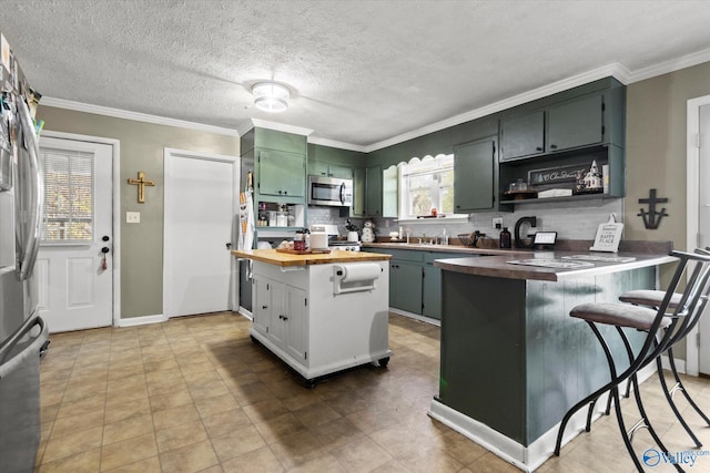 kitchen featuring kitchen peninsula, ornamental molding, a textured ceiling, butcher block countertops, and a breakfast bar area