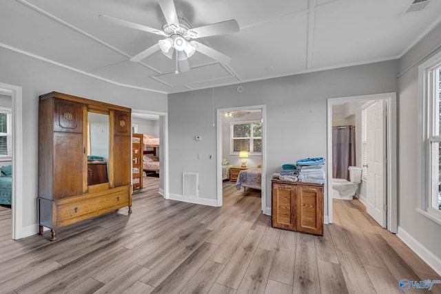 interior space featuring multiple windows, ceiling fan, ensuite bath, and light wood-type flooring