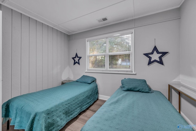 bedroom with hardwood / wood-style floors and wood walls