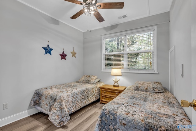 bedroom featuring hardwood / wood-style flooring, ceiling fan, and crown molding