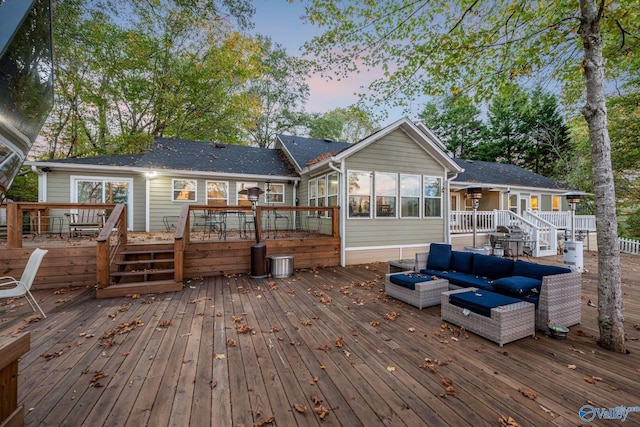 deck at dusk with outdoor lounge area and a sunroom