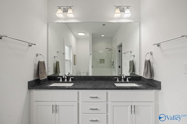 bathroom with a shower stall, double vanity, and toilet