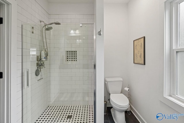 bathroom featuring a shower stall, toilet, and baseboards