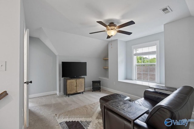 living area with a ceiling fan, light colored carpet, baseboards, built in features, and a wood stove