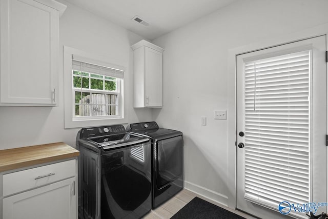 laundry room with separate washer and dryer, cabinet space, baseboards, and light wood-style floors