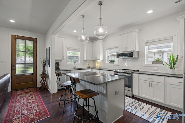 kitchen with appliances with stainless steel finishes, a sink, white cabinets, a center island, and recessed lighting