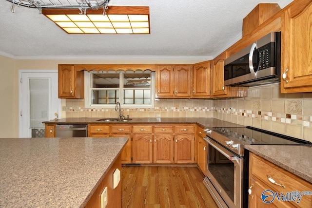 kitchen with light wood-style flooring, brown cabinets, appliances with stainless steel finishes, and a sink