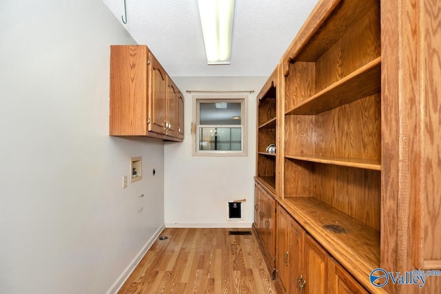 laundry area with electric dryer hookup, light wood-type flooring, washer hookup, baseboards, and cabinet space