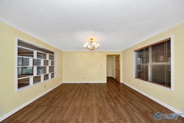 spare room with baseboards, an inviting chandelier, ornamental molding, a textured ceiling, and wood finished floors
