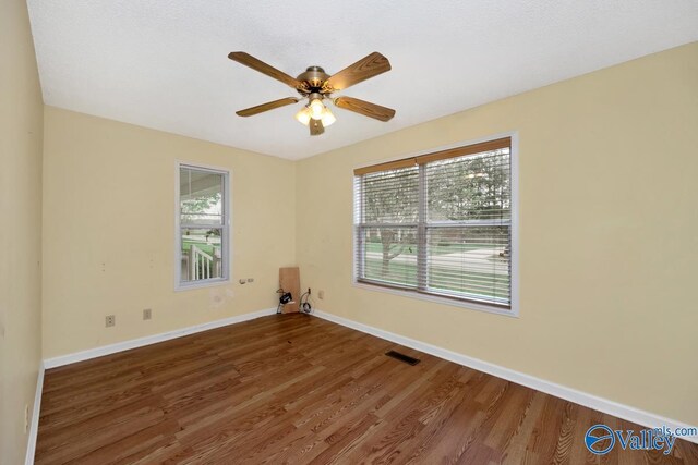 spare room with plenty of natural light, baseboards, a ceiling fan, and wood finished floors