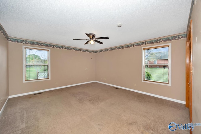 carpeted spare room featuring baseboards, a ceiling fan, and a wealth of natural light